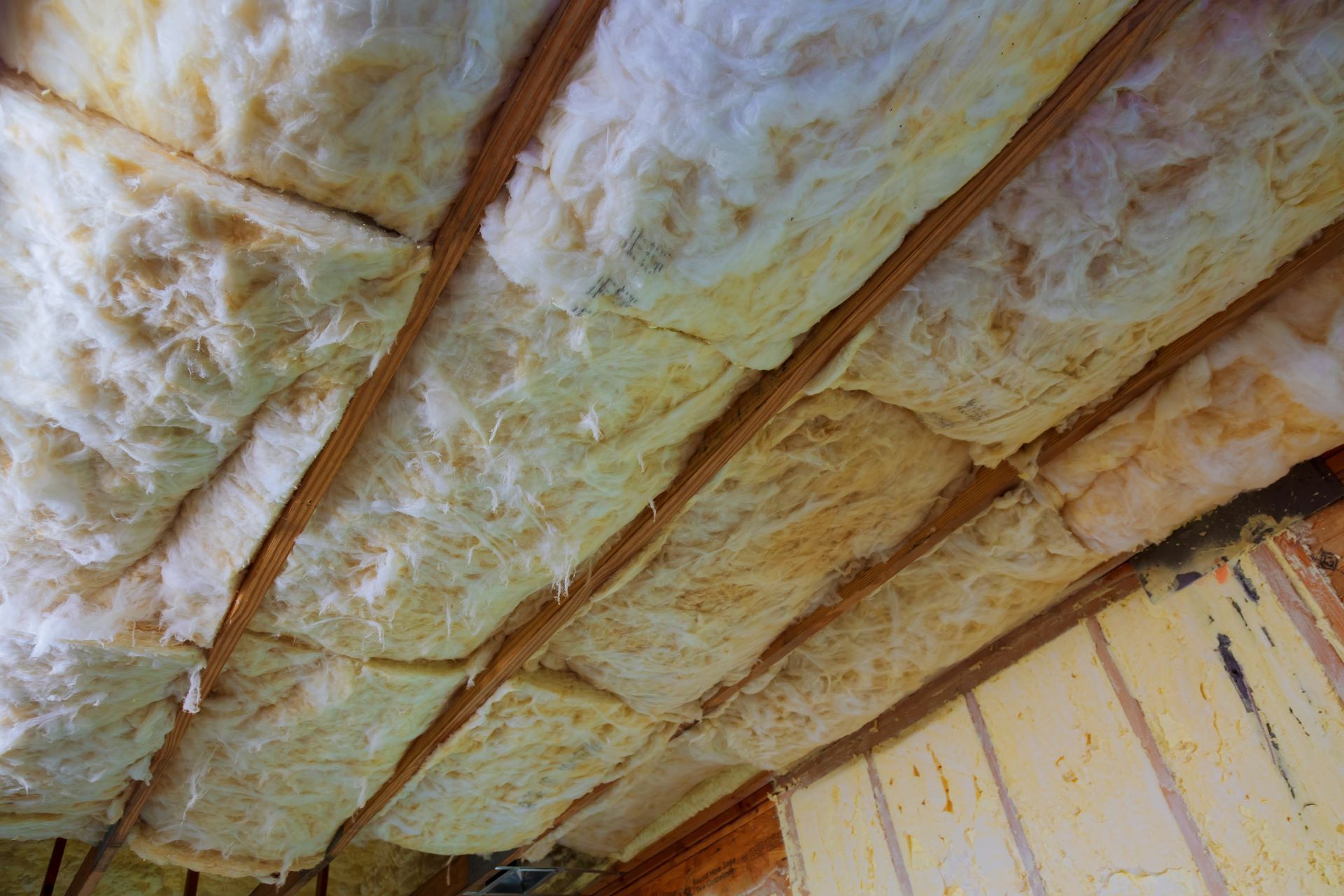 Close-up of strips of pink fiberglass insulation in a wall of a new building.