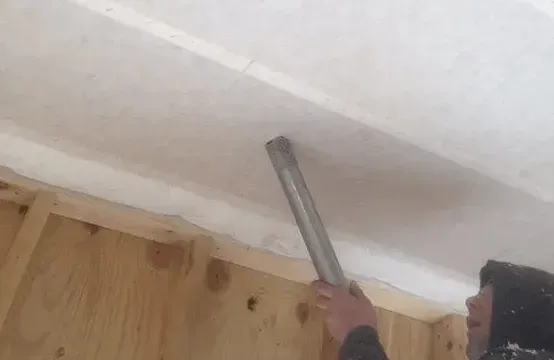 A person is using a vacuum cleaner to clean a ceiling.