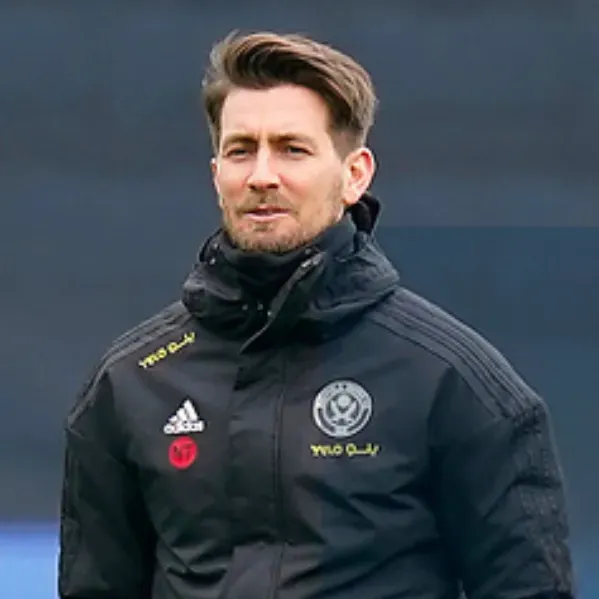 Man in black Adidas jacket, logo visible. Outdoors, looking forward.