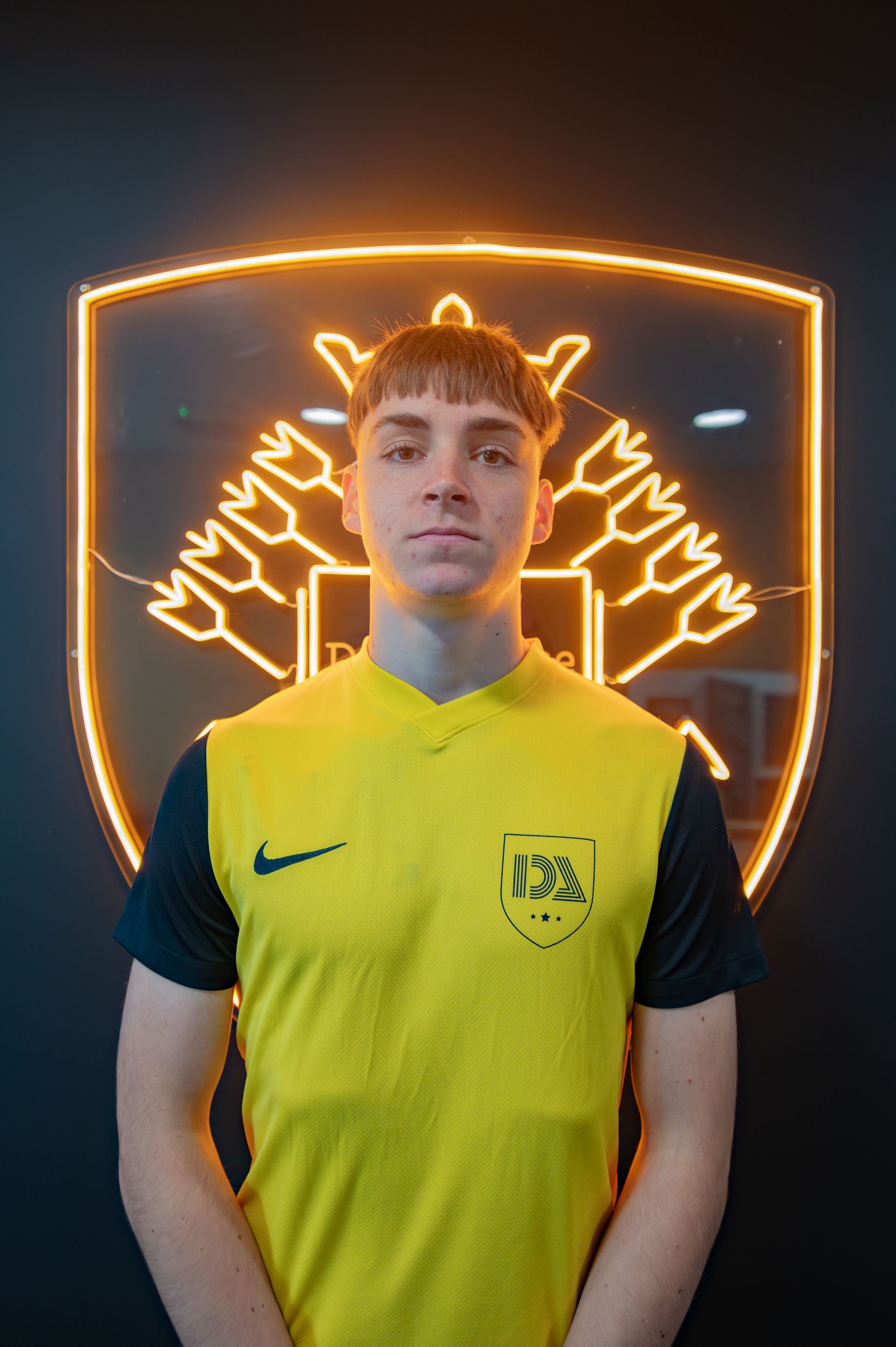 Man in yellow jersey stands in front of a glowing emblem.