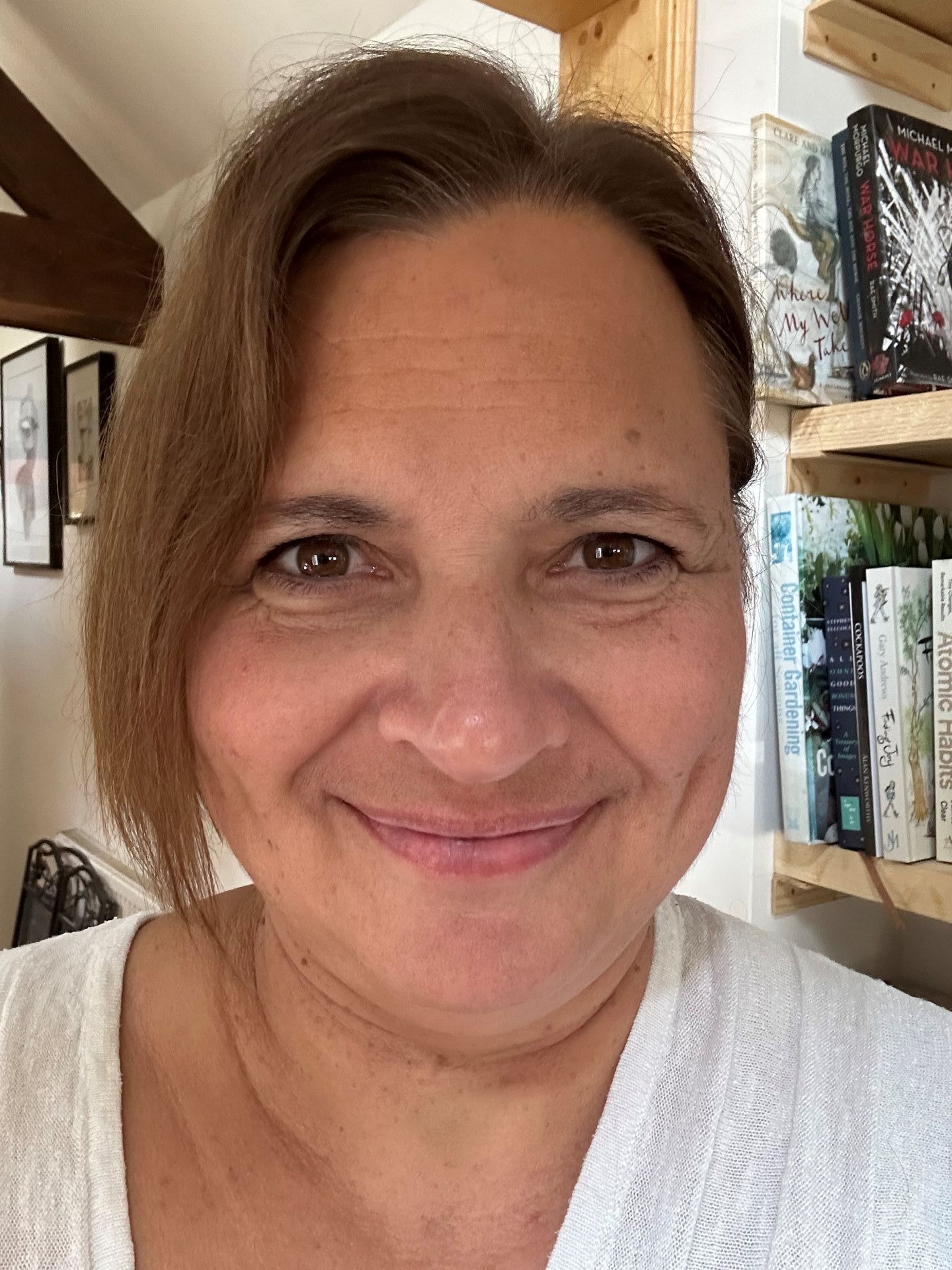 a woman is smiling for the camera in front of a bookshelf .