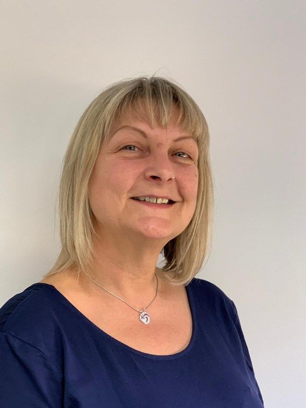 a woman wearing a blue shirt and a necklace is smiling for the camera 