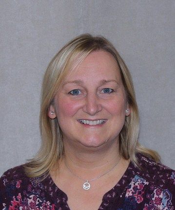 a woman wearing a necklace and a floral shirt is smiling for the camera 