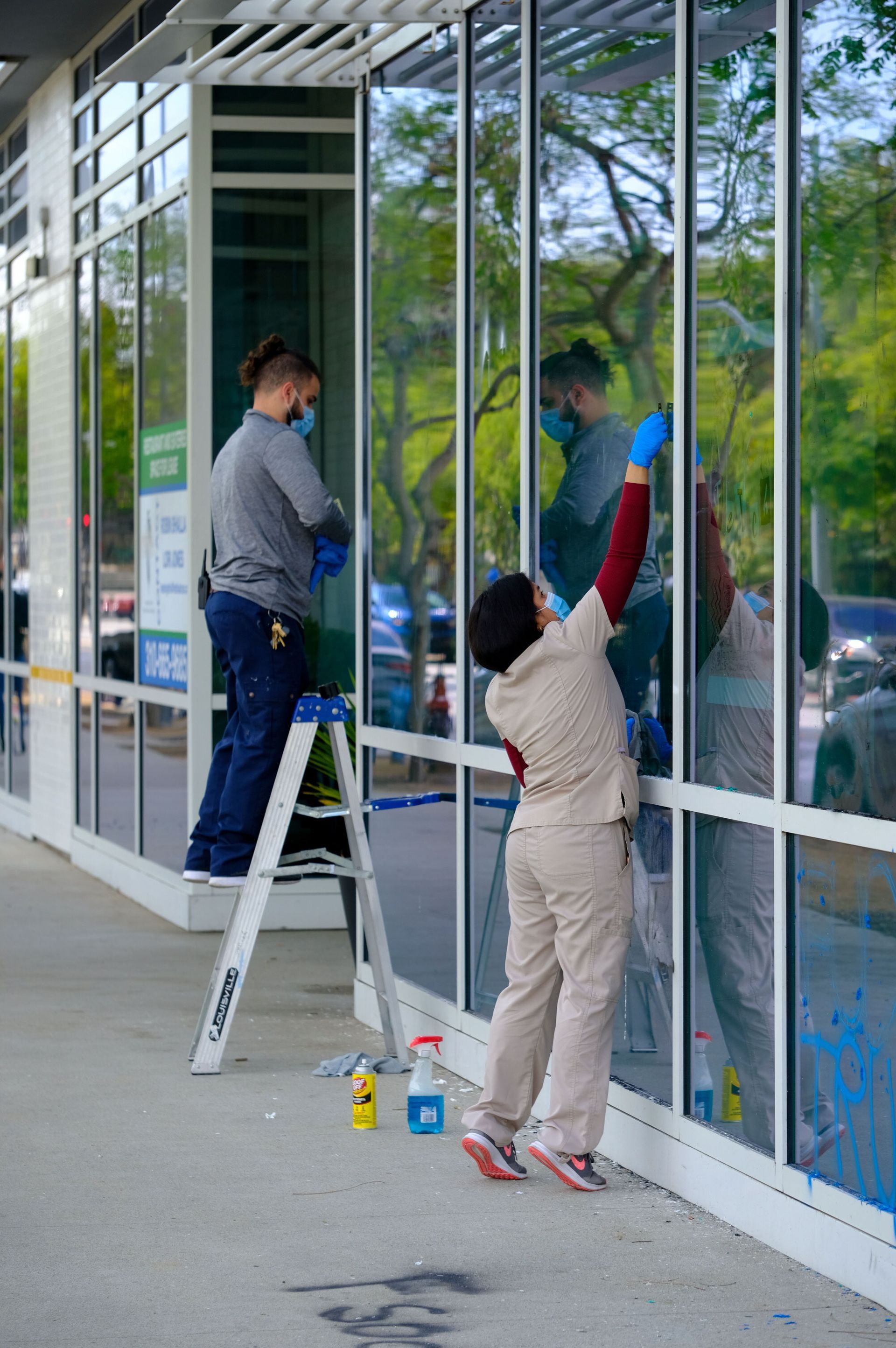 A man and a woman are cleaning the windows of a building.