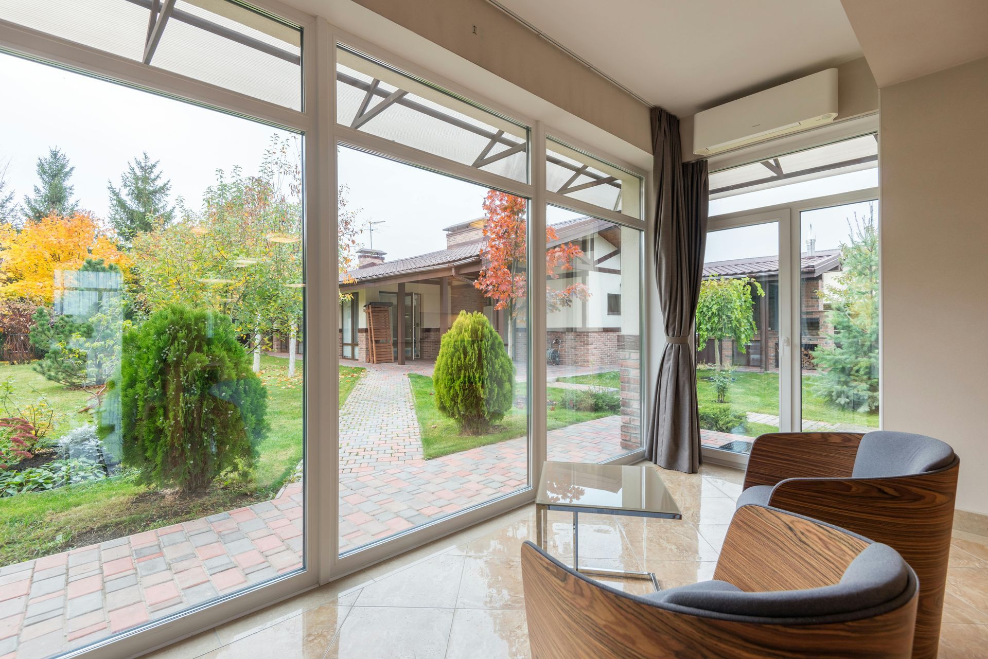 A living room with a lot of windows and a view of a garden.
