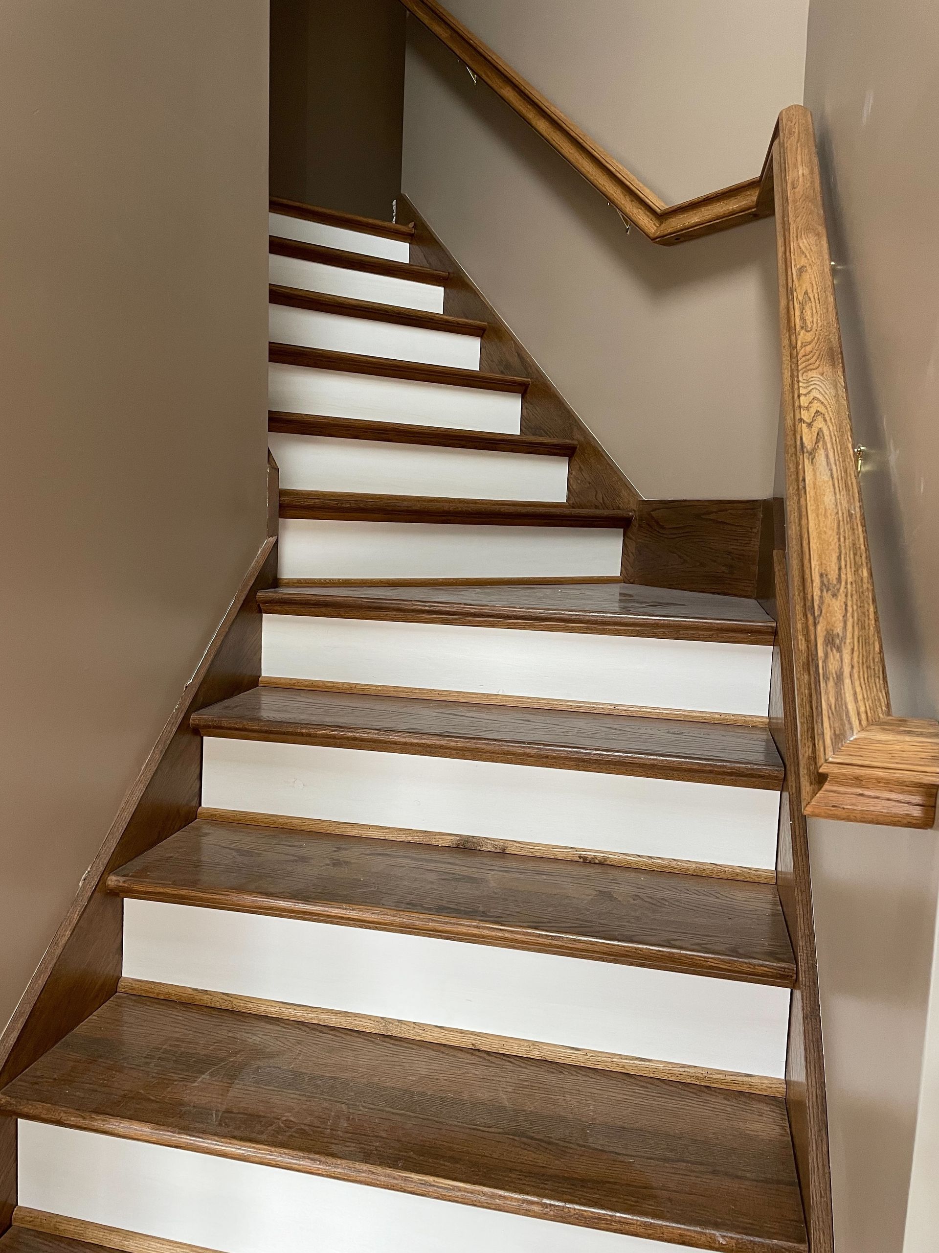 A wooden staircase with white steps and a wooden railing