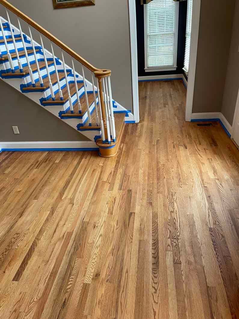 A wooden floor with a staircase in the background.