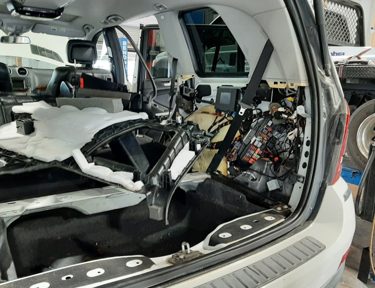 Car trunk interior disassembled, revealing wires, components, and structure | Crown Car Care