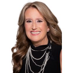 Smiling woman in a black top with layered pearl necklaces on a white background