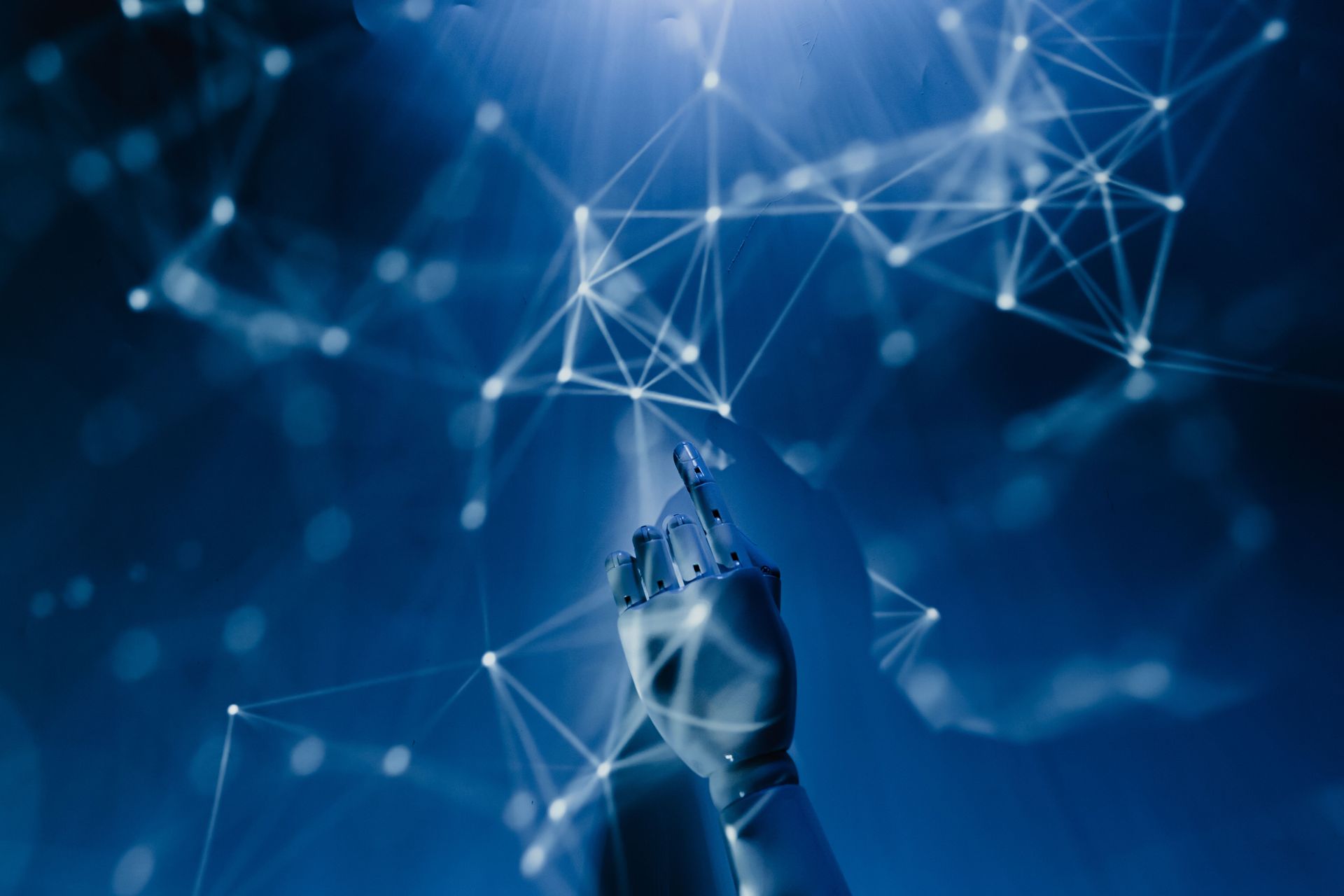 Robotic hand reaching toward glowing digital network lines on a blue background