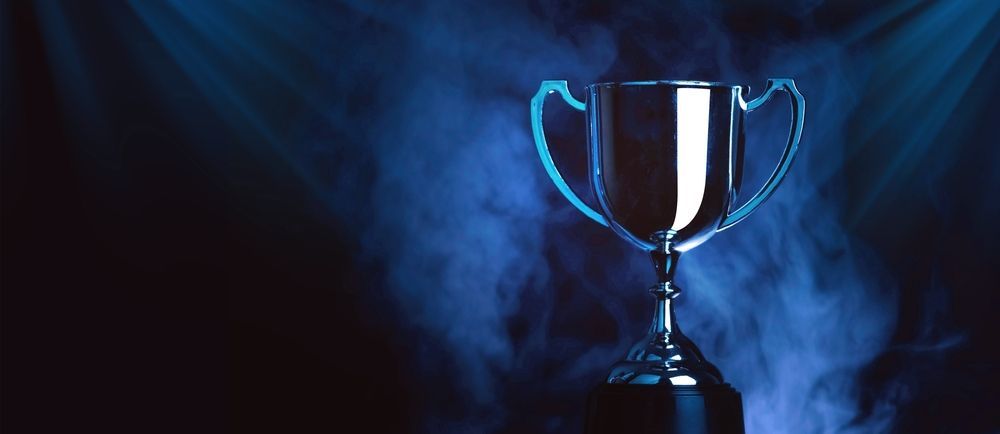 Silver trophy with blue handles on a dark smoky background