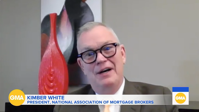 Man speaking on GMA, wearing glasses, with a red-and-black abstract sculpture behind him.