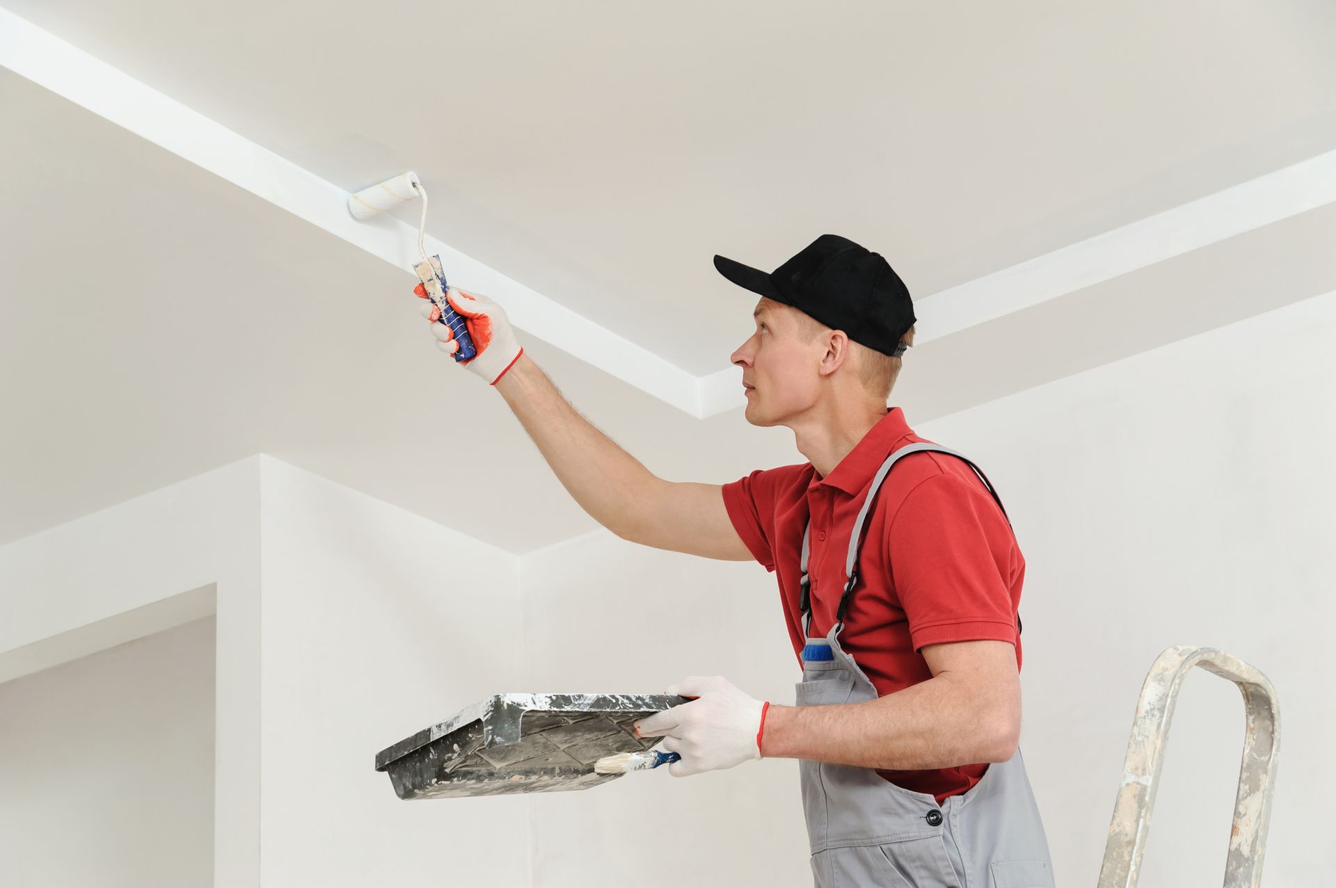 A man is painting the ceiling with a roller — North Liberty, IA — DeltaPro Painting & Remodeling A man is painting the ceiling with a roller — North Liberty, IA — DeltaPro Painting & Remodeling