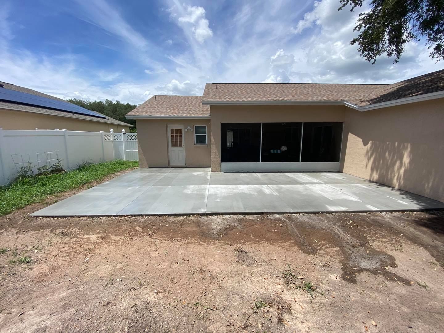 Front view of a tan house with a new concrete driveway and large black garage doors
