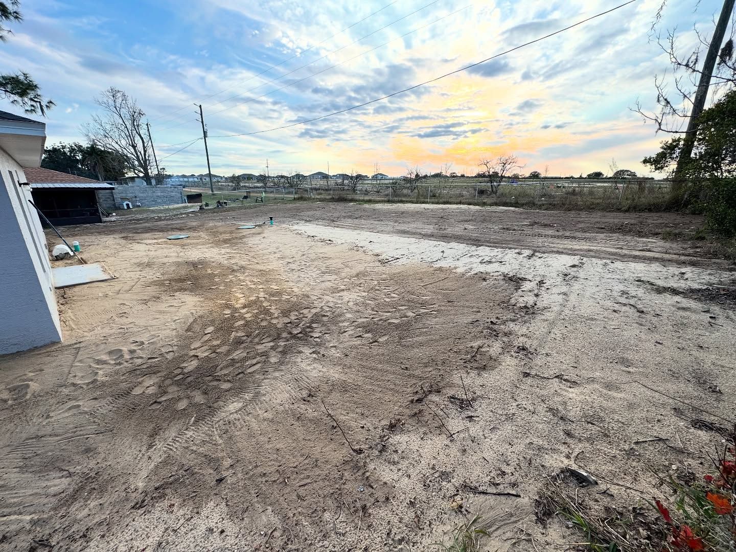 Cleared lot with dirt ground under a colorful sunset sky.