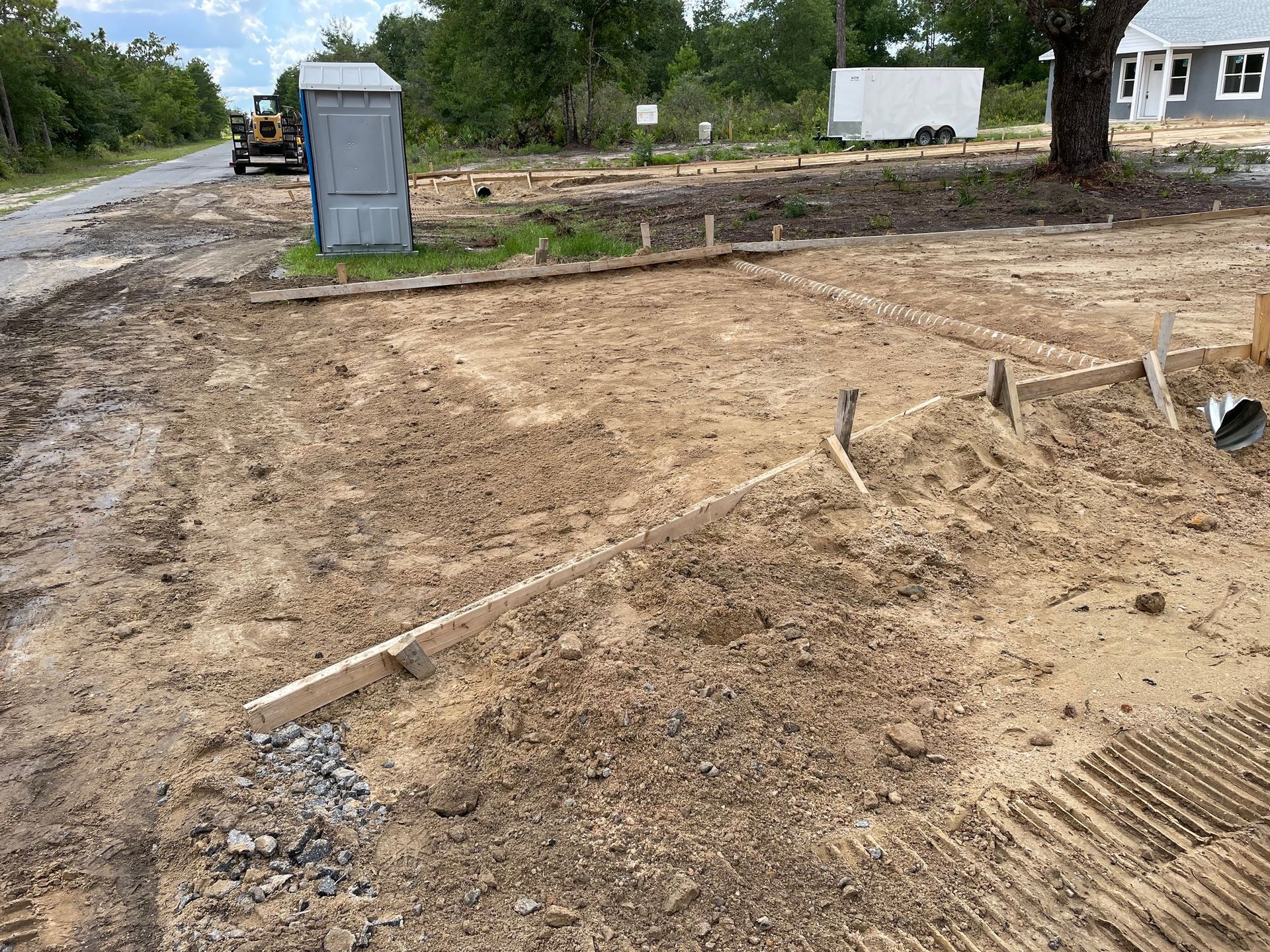 A construction site with a portable toilet and a bulldozer in the background.