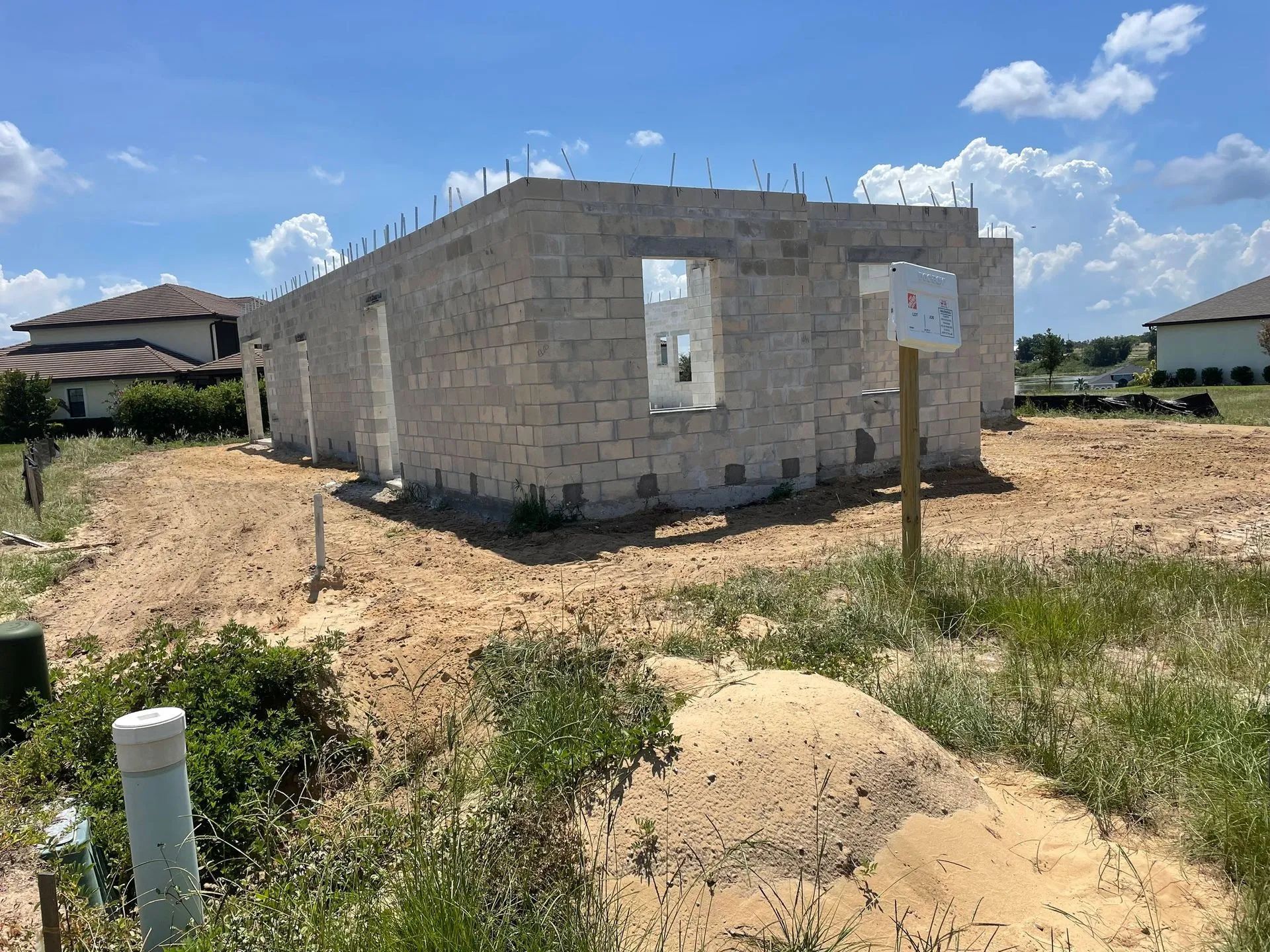 Construction site with unfinished concrete block house under a blue sky.