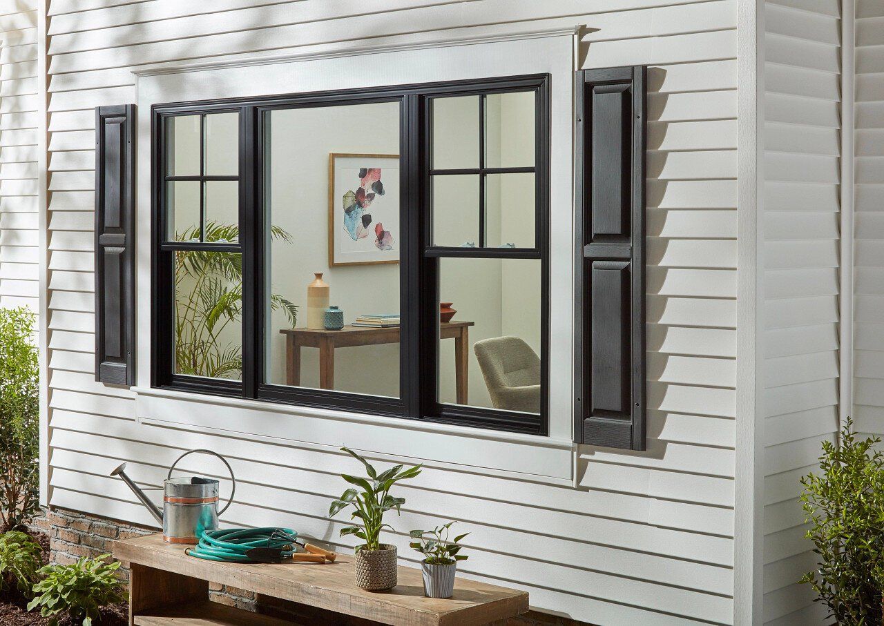 A white house with a large window and black shutters.