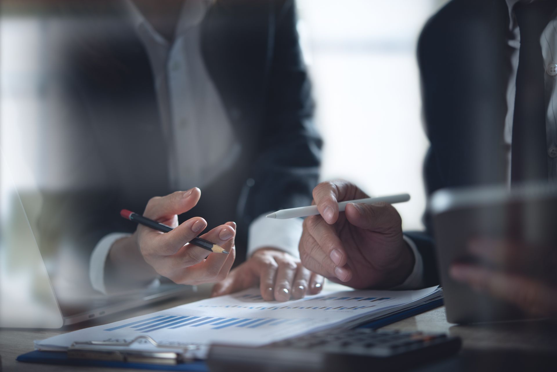 Hands writing on a document at a desk during a business meeting