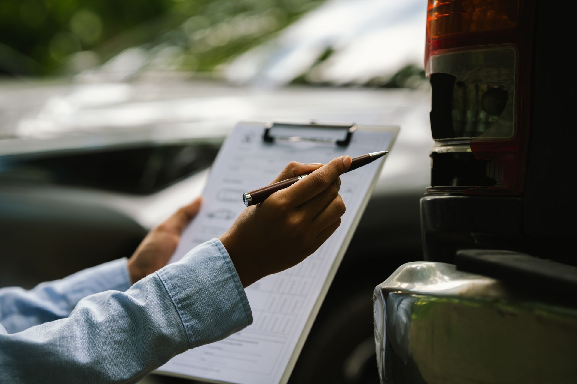 Person writing on a clipboard beside a vehicle at night