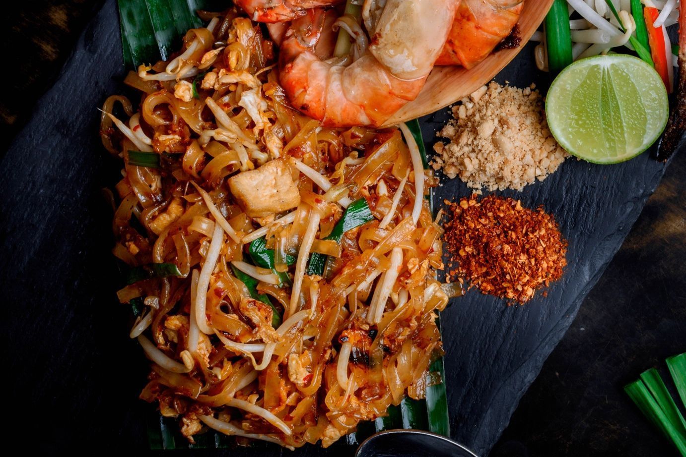 An organic Pad Thai meal kit in a black-and-white striped fabric drawstring bag with a yellow rope handle.