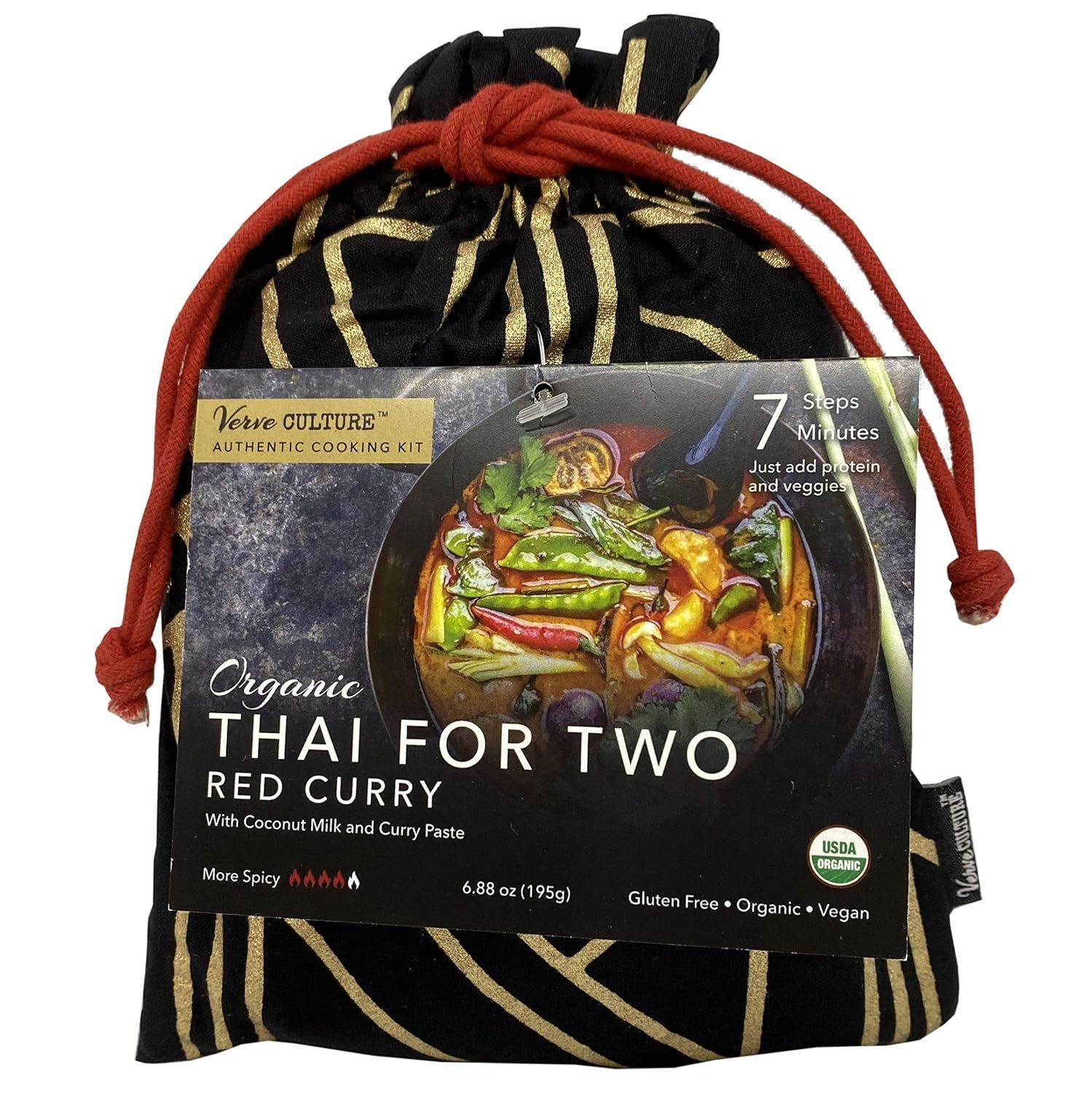 A drawstring bag with gold patterns contains an organic Thai Red Curry kit with a product label.