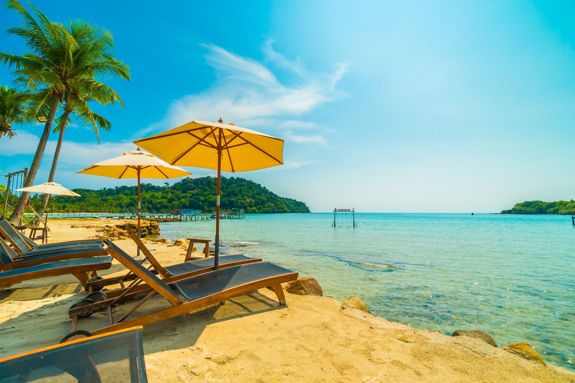 There are chairs and umbrellas on the beach near the water.