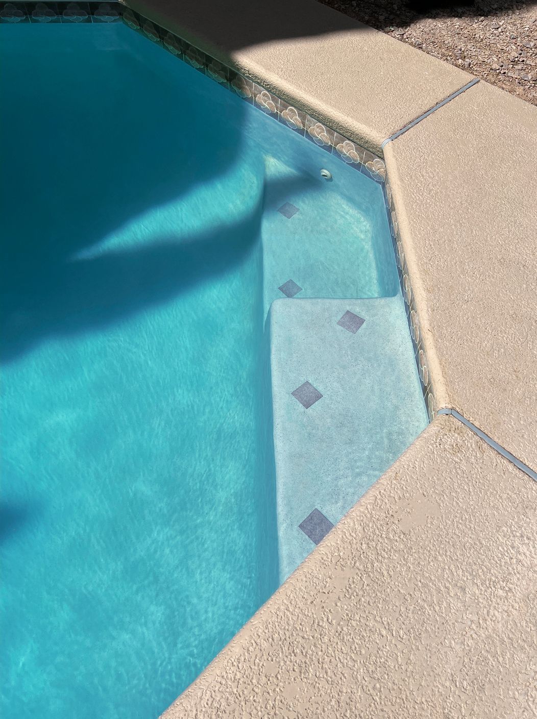 A close up of a swimming pool with blue water and steps.