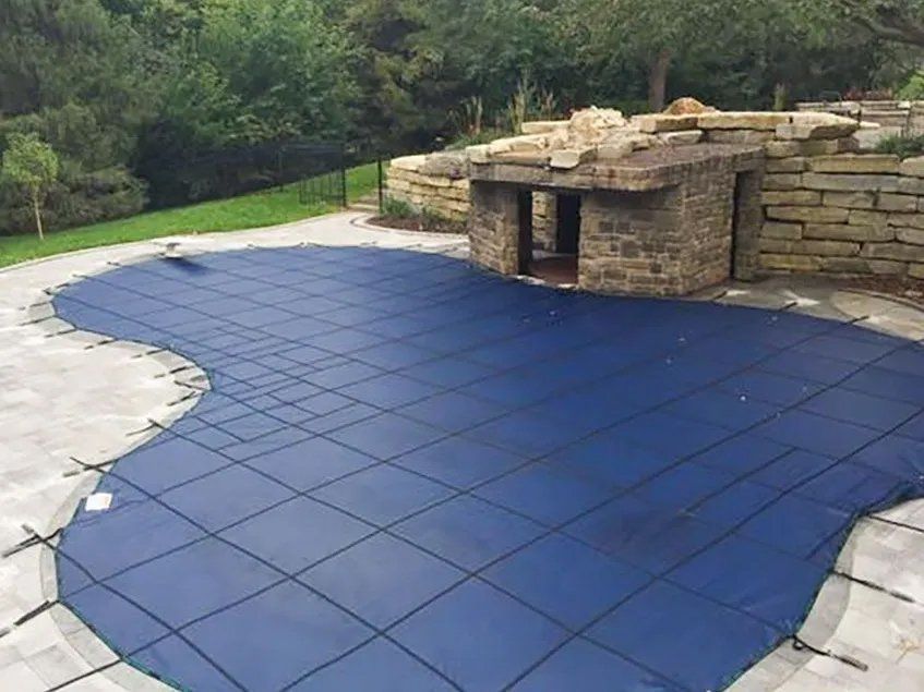 A blue swimming pool cover is sitting on top of a tiled patio.