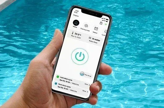 A person is holding a cell phone in front of a pool.