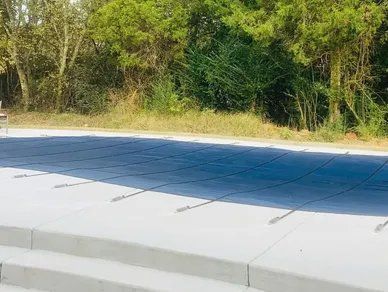 A swimming pool with a blue cover on it and trees in the background.