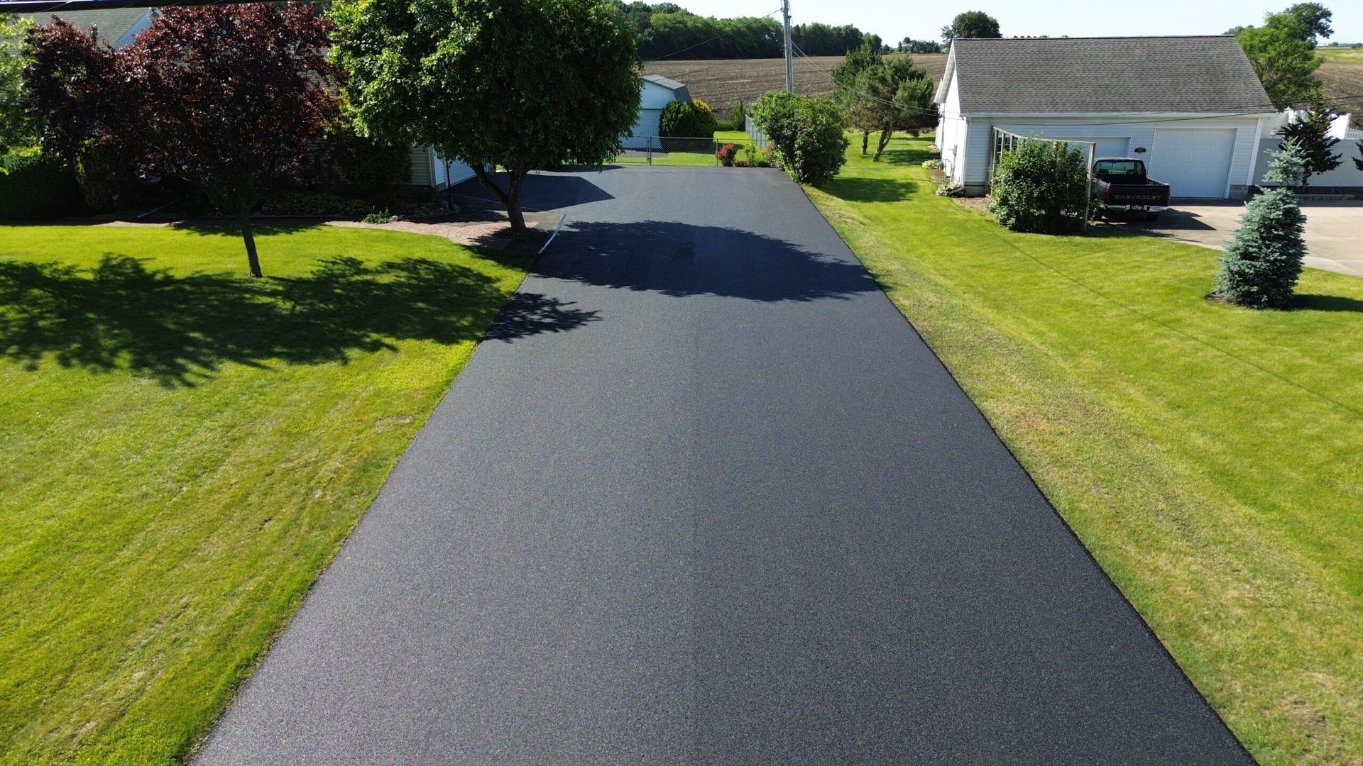 Road paving crew beside a yellow asphalt paver on a freshly laid black road in a desert setting