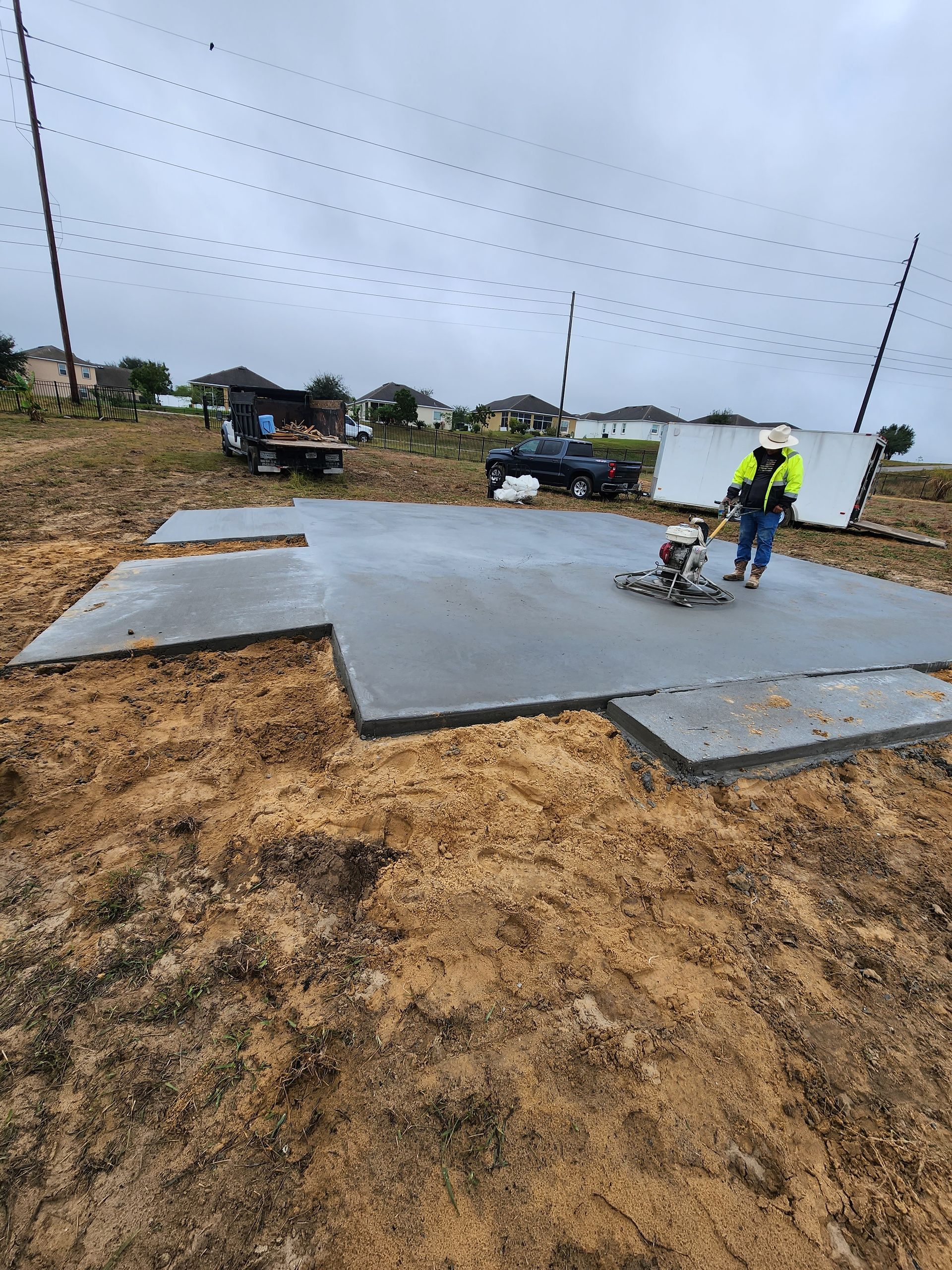 A man is working on a concrete floor in a field.