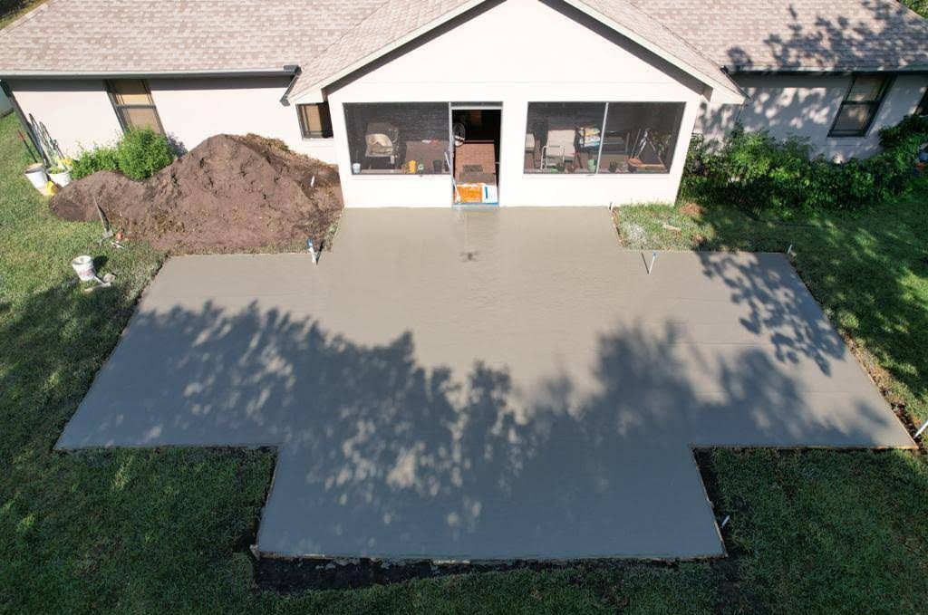 An aerial view of a house with a concrete patio in front of it
