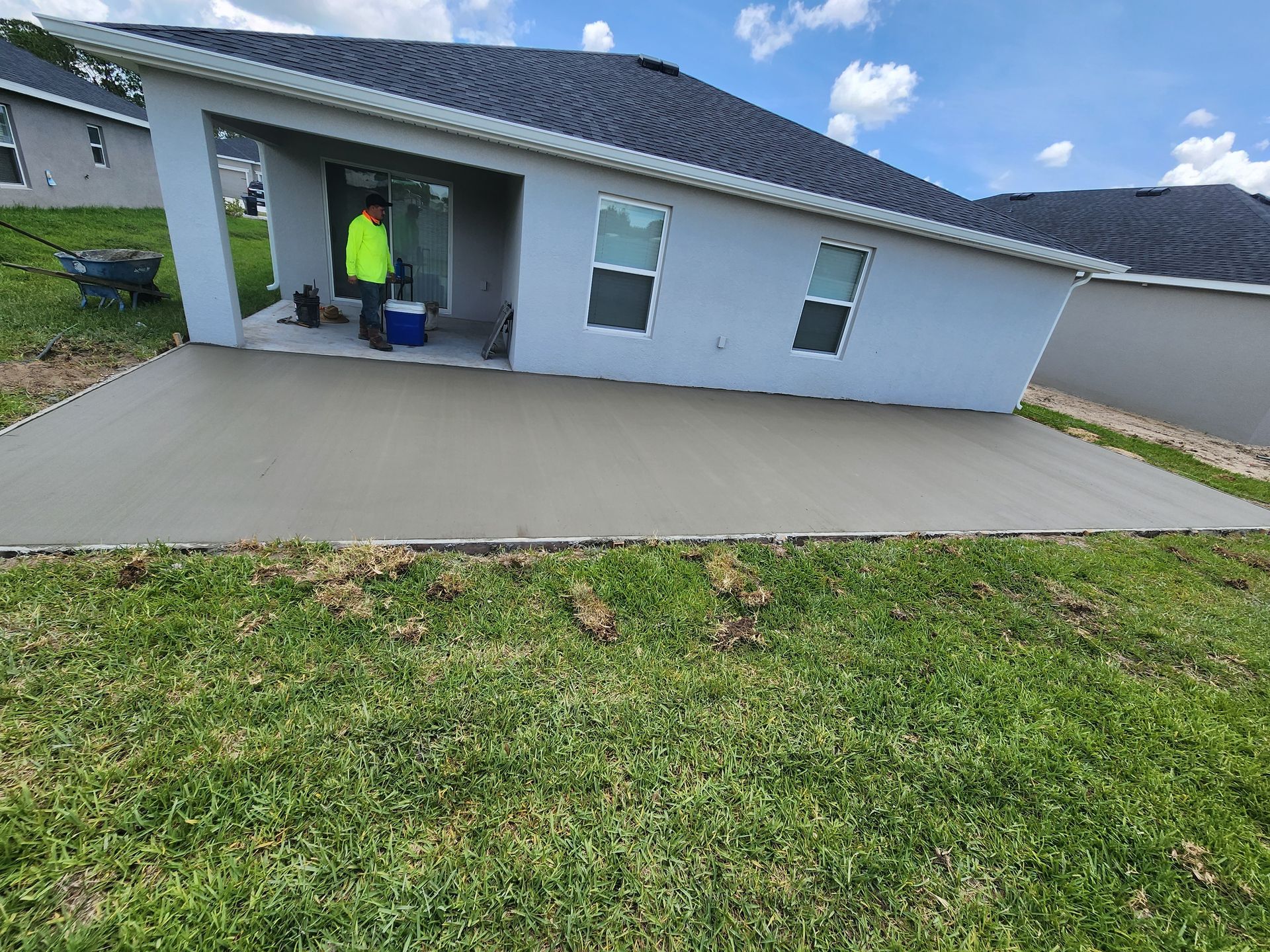 A man in a yellow vest is standing in front of a house.