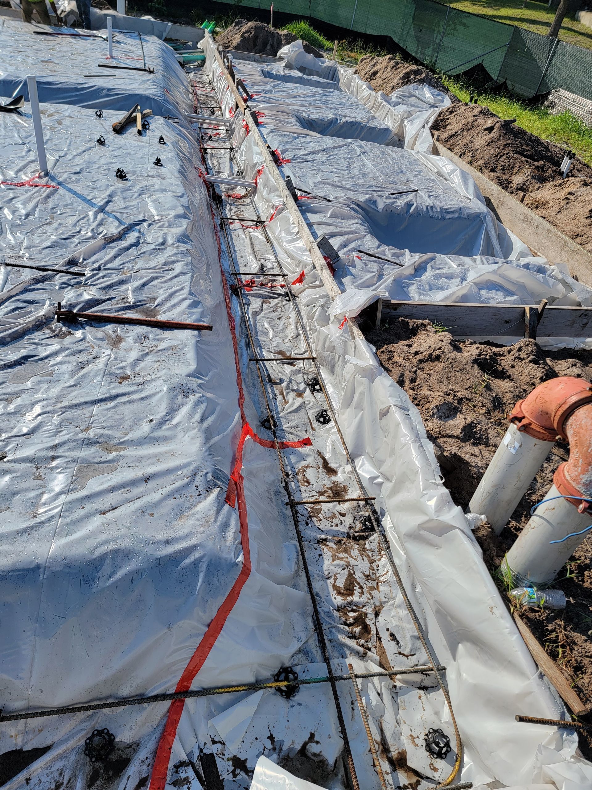 A man is working on a concrete foundation covered in plastic.
