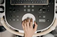 A hand operates the trackball control panel of an ultrasound machine.