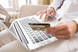 Person using a laptop while holding a credit card, making an online payment.
