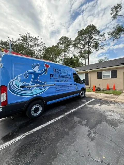 Blue van with beach mural parked in a lot beside a building and orange cones