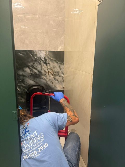 Worker in blue shirt applies trim around a wall panel with a red tool in a doorway.