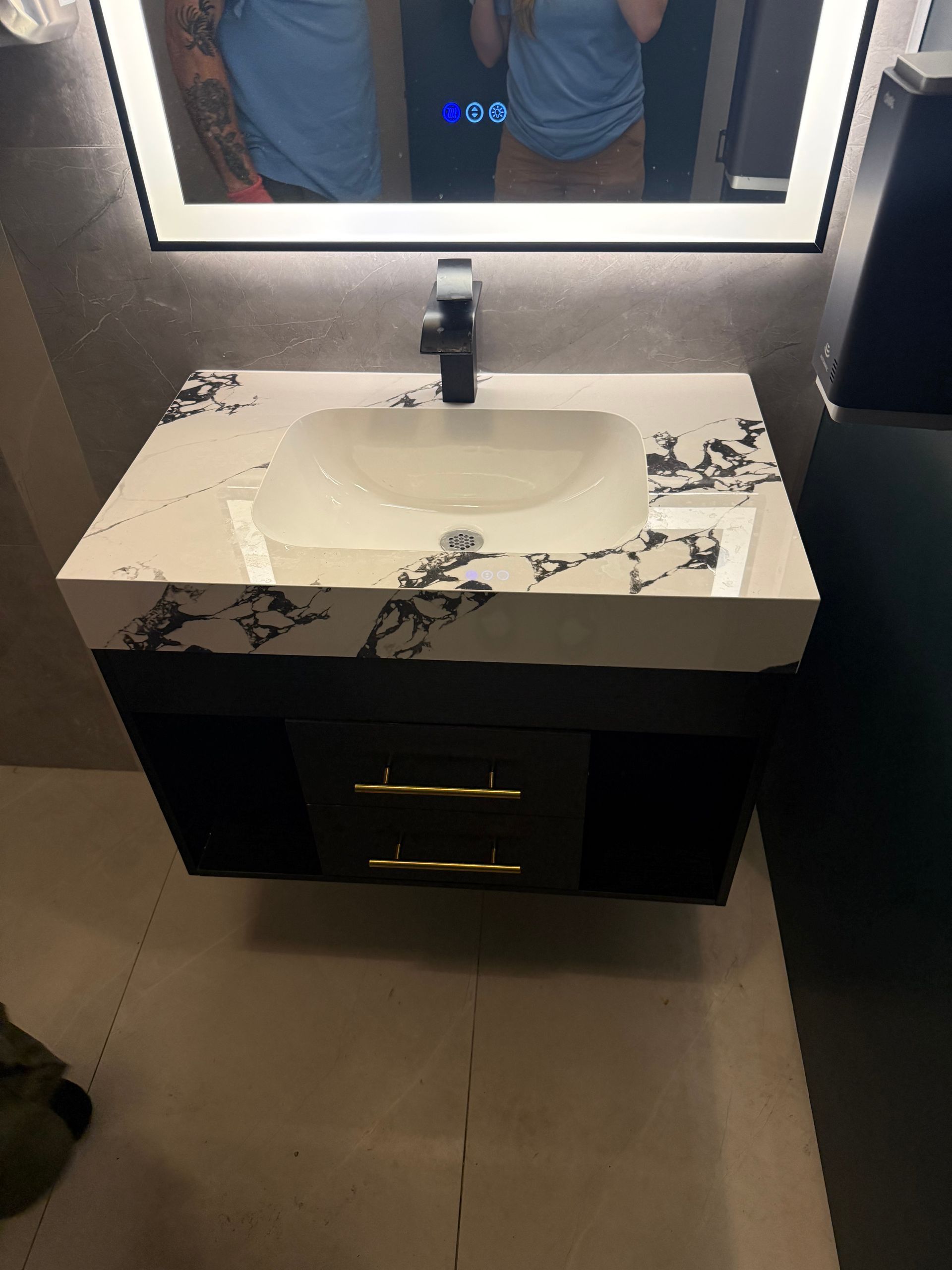 Modern bathroom sink with black vanity, mirror, and water damage or debris on the countertop and basin