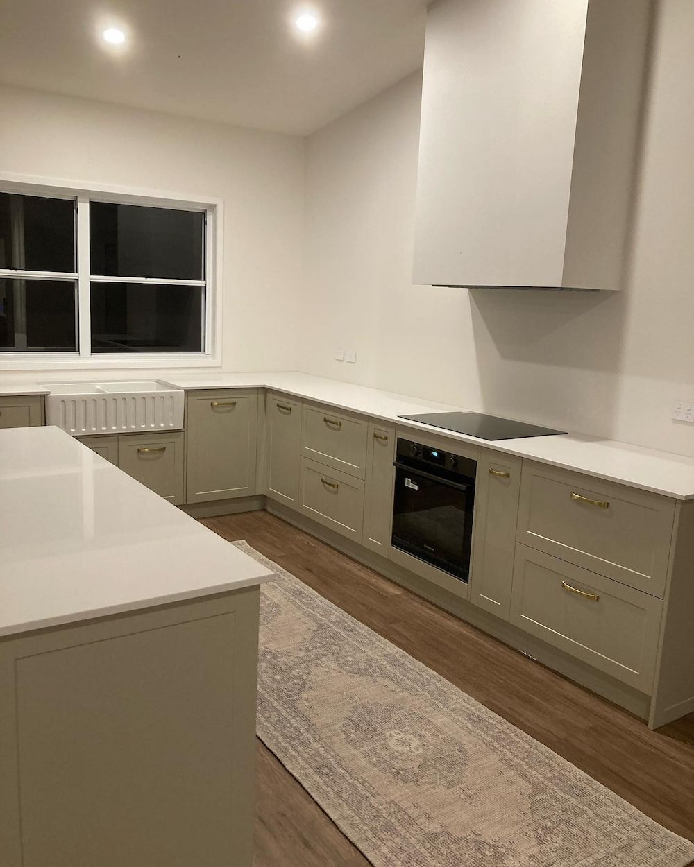 Modern kitchen with light green cabinets, white countertops, and an island — JGD Constructions in Lake Eacham, QLD
