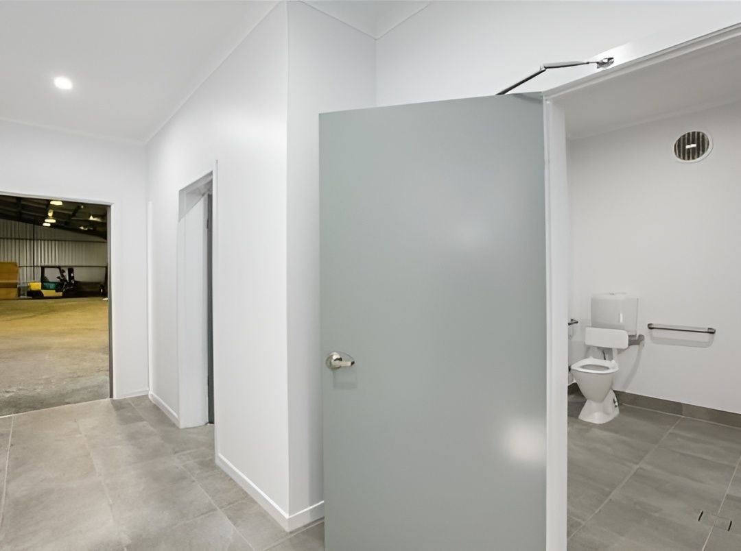 A Light Gray Door Opens Into a White-walled Bathroom With a Toilet — JGD Constructions in Lake Eacham, QLD