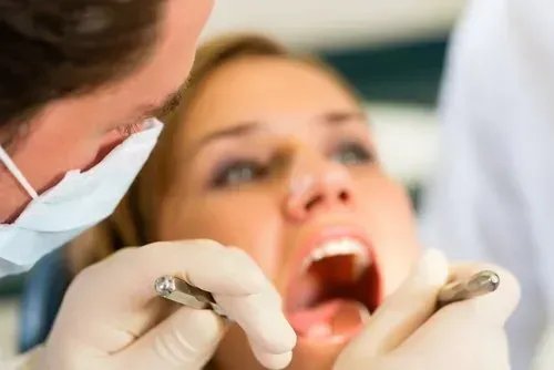 A woman is getting her teeth examined by a dentist. A woman is getting her teeth examined by a dentist.