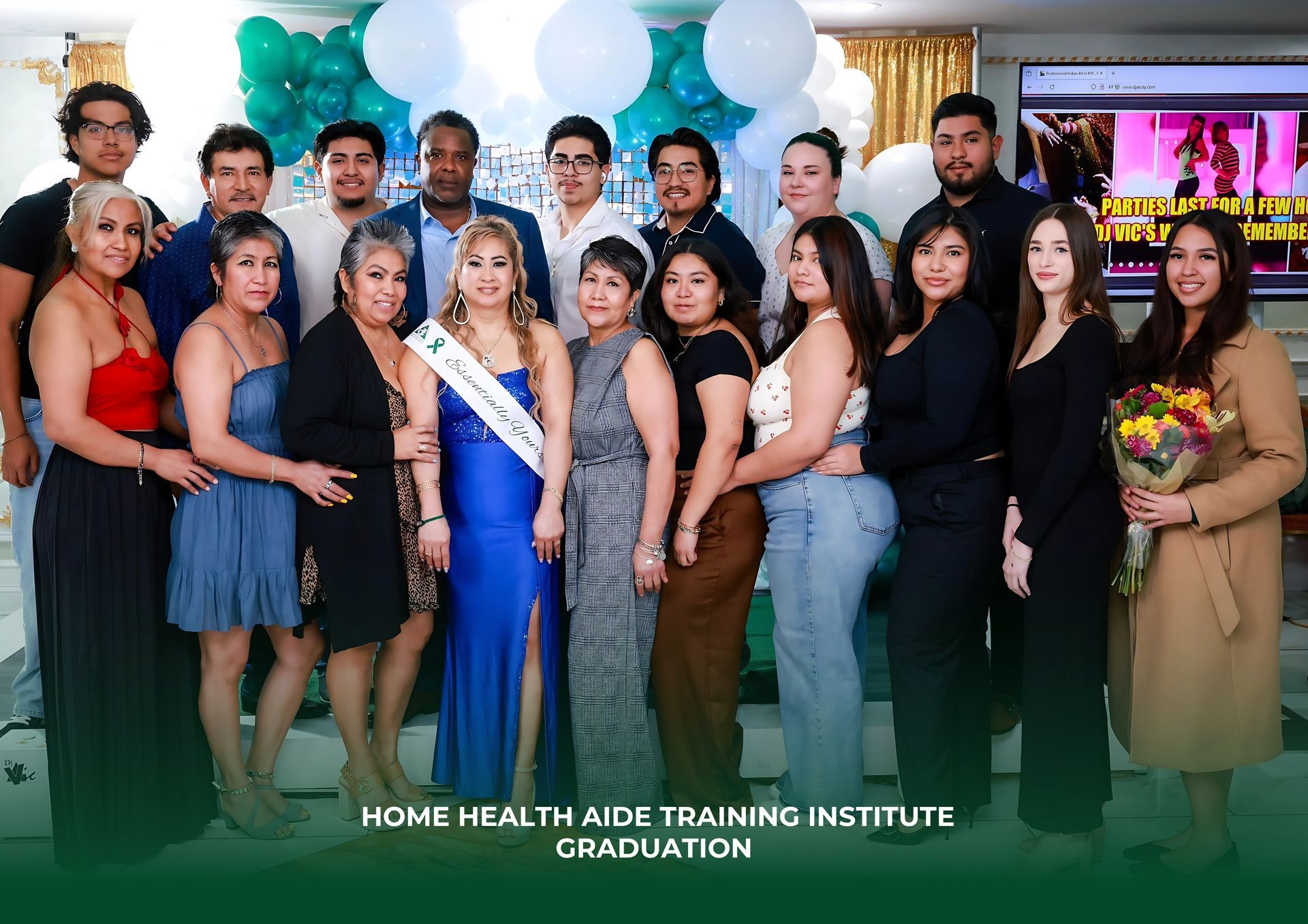 A group posing at a Home Health Aide Training Institute graduation, with one graduate in a blue gown and sash in the center.