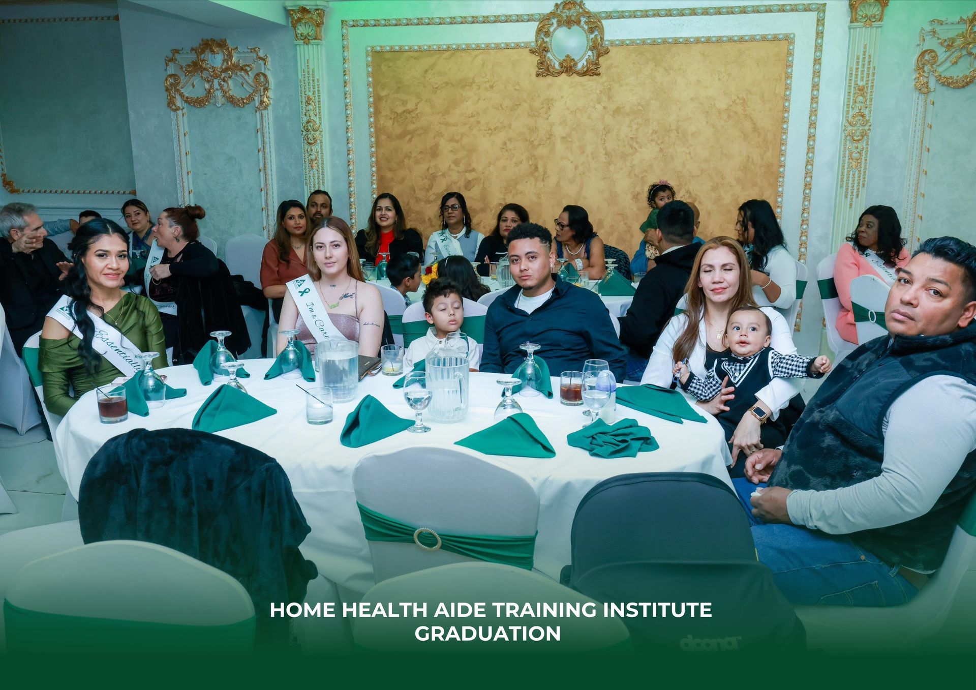 Group of people seated at a table for a Home Health Aide Training Institute graduation in a decorated event room.