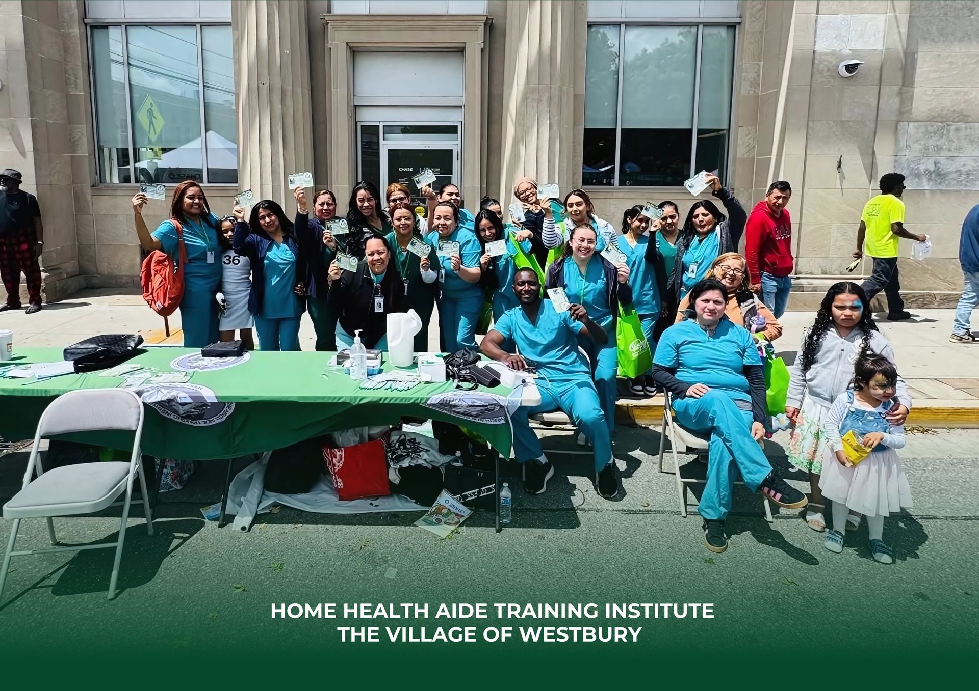 A group wearing teal scrubs stands behind a green table at an outdoor event, representing Home Health Aide Training.