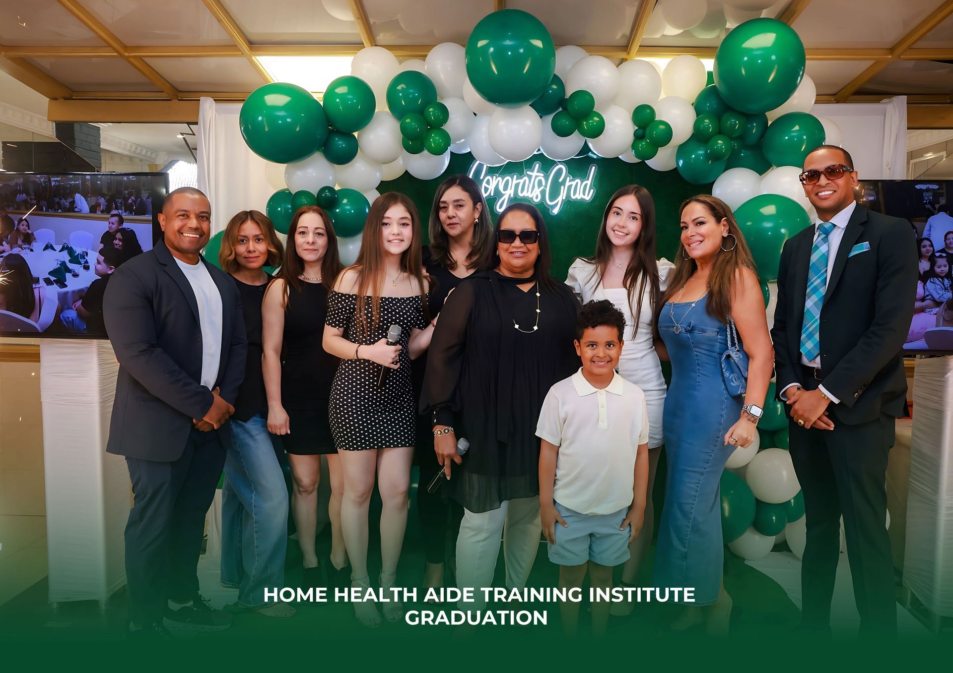 A group poses in front of a green balloon arch and 