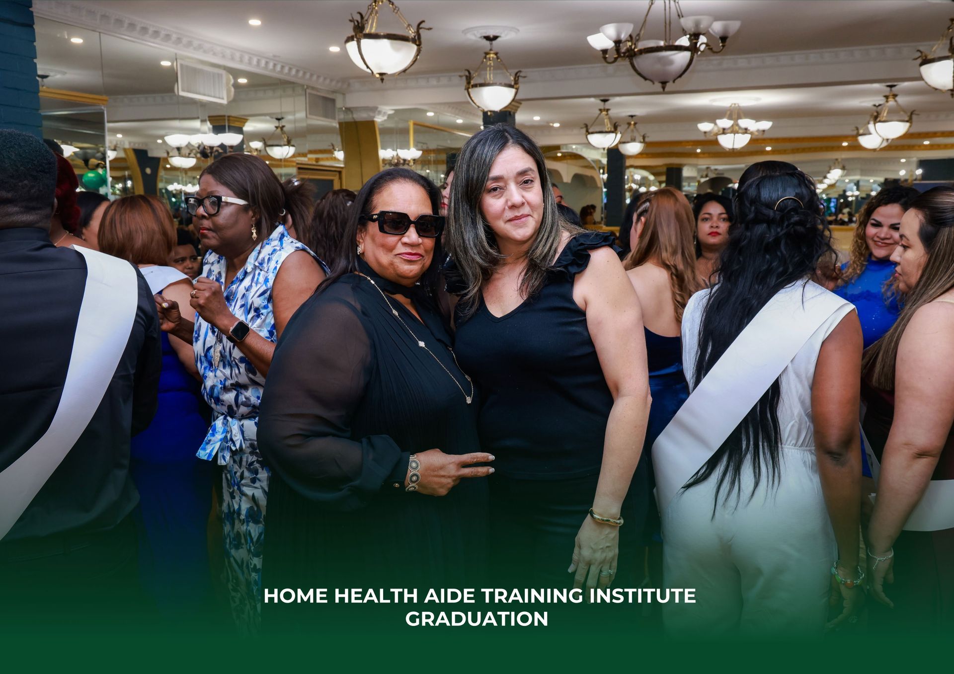A group of people celebrating at a Home Health Aide Training Institute graduation ceremony in a decorated event hall.