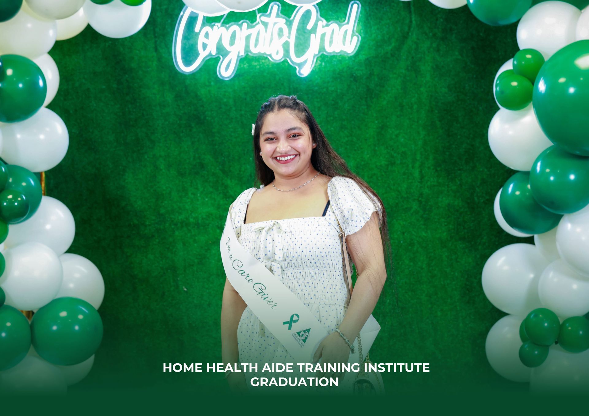 A graduate smiles in front of a green wall with 